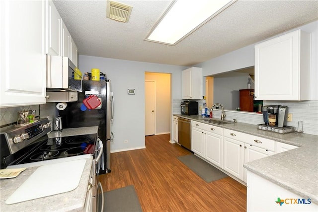 kitchen with sink, white cabinetry, hardwood / wood-style floors, backsplash, and stainless steel appliances