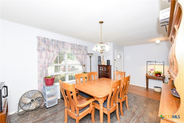 dining room with dark wood-type flooring, a notable chandelier, and a textured ceiling