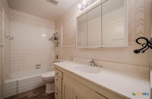 full bathroom with vanity, wood finished floors, visible vents, wallpapered walls, and toilet