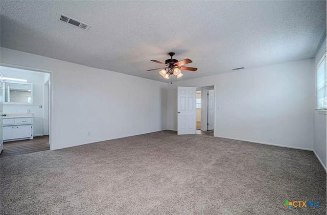 unfurnished bedroom featuring visible vents, carpet, and a textured ceiling