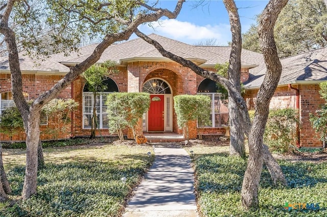 view of front of property with brick siding and roof with shingles