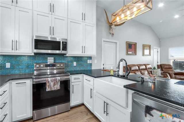 kitchen featuring a sink, stainless steel appliances, tasteful backsplash, vaulted ceiling, and open floor plan