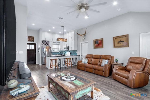 living area with a ceiling fan, recessed lighting, visible vents, vaulted ceiling, and wood finished floors