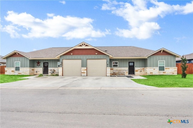 craftsman house with an attached garage, roof with shingles, a front yard, and stone siding