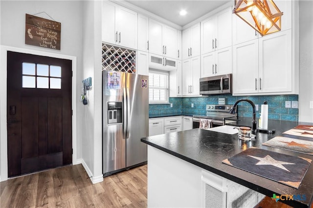 kitchen with white cabinets, dark countertops, appliances with stainless steel finishes, and light wood-style floors