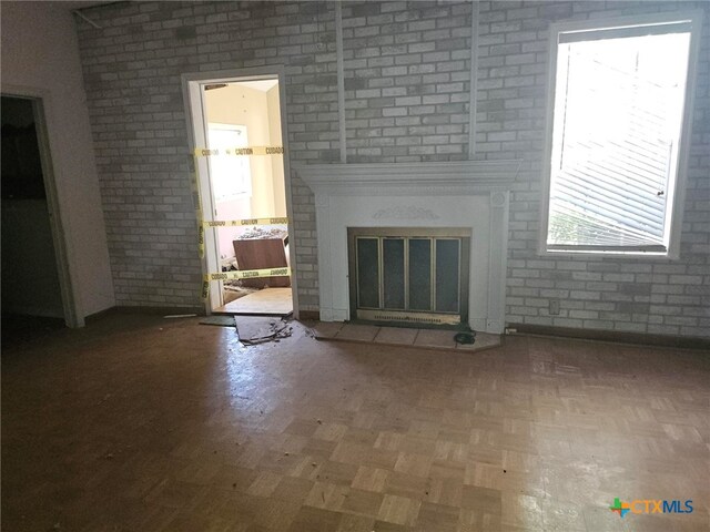 unfurnished living room with brick wall and a fireplace