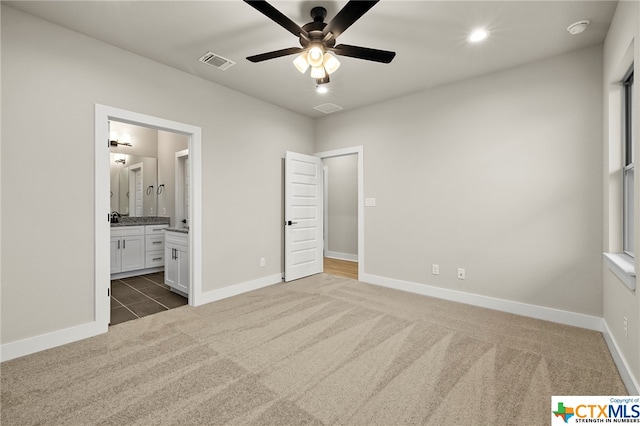 unfurnished bedroom with connected bathroom, ceiling fan, and dark carpet