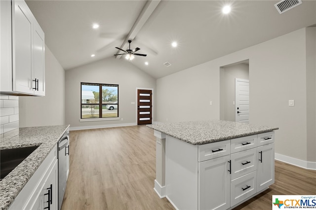 kitchen featuring vaulted ceiling with beams, light hardwood / wood-style floors, white cabinetry, and light stone counters