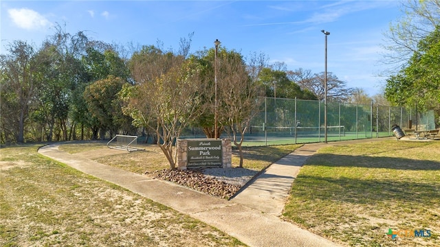 view of property's community featuring a lawn and fence