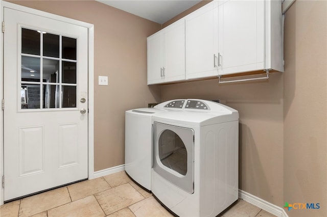 clothes washing area with washer and dryer, light tile patterned floors, cabinet space, and baseboards