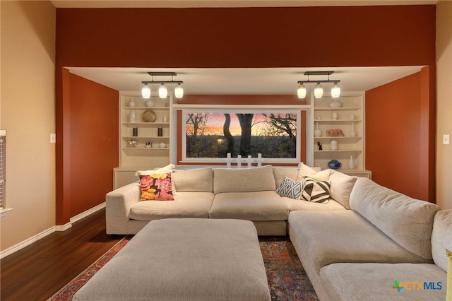 living room with built in shelves, baseboards, and dark wood-style flooring