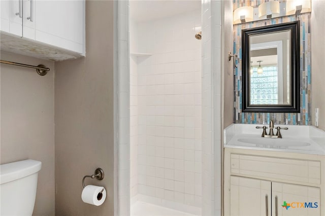 bathroom featuring tiled shower, toilet, and vanity