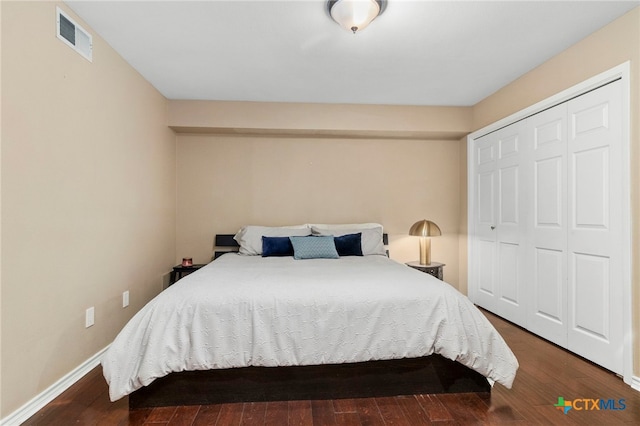 bedroom with dark wood finished floors, visible vents, baseboards, and a closet