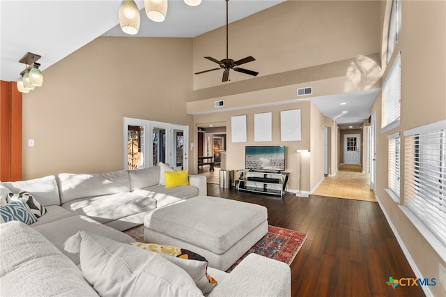 living room with hardwood / wood-style floors, baseboards, visible vents, and high vaulted ceiling