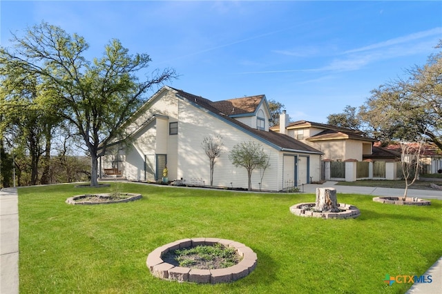 view of home's exterior with a garage, a fire pit, a lawn, and driveway