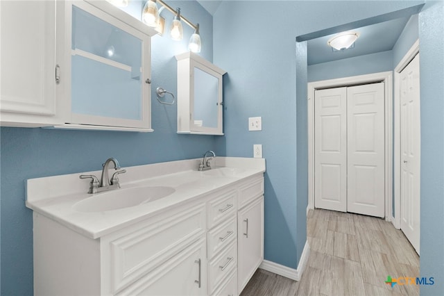 bathroom with double vanity, baseboards, and a sink