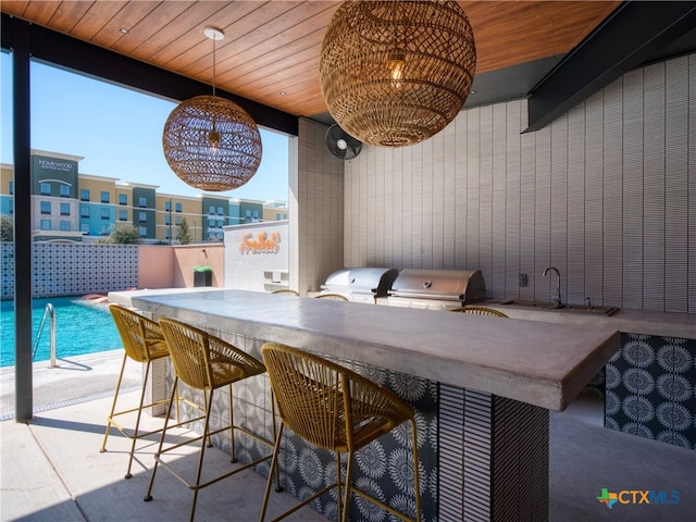 view of patio featuring outdoor wet bar, a fenced in pool, a grill, and area for grilling