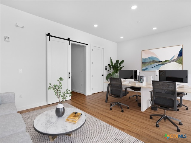 home office featuring a barn door, baseboards, wood finished floors, and recessed lighting