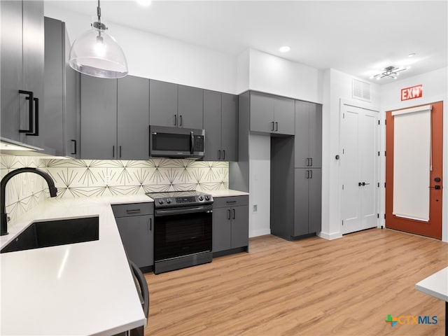 kitchen featuring light wood-style flooring, a sink, visible vents, electric stove, and stainless steel microwave