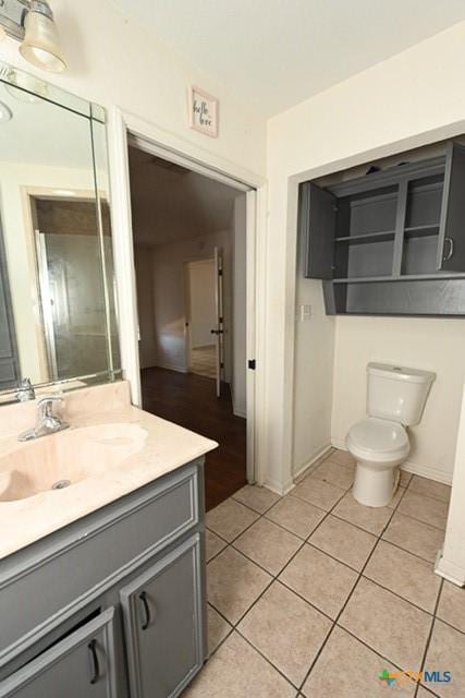 bathroom with tile patterned flooring, vanity, and toilet