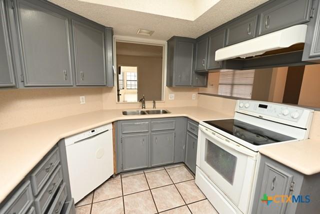 kitchen with light tile patterned floors, white appliances, gray cabinetry, and sink