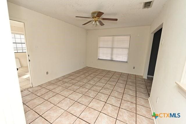 unfurnished room featuring ceiling fan, light tile patterned floors, and a textured ceiling