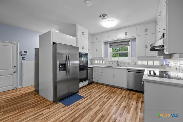 707 W Thompson Ave, Temple, TX 76501 - kitchen with black appliances, a sink, under cabinet range hood, and light wood finished floors