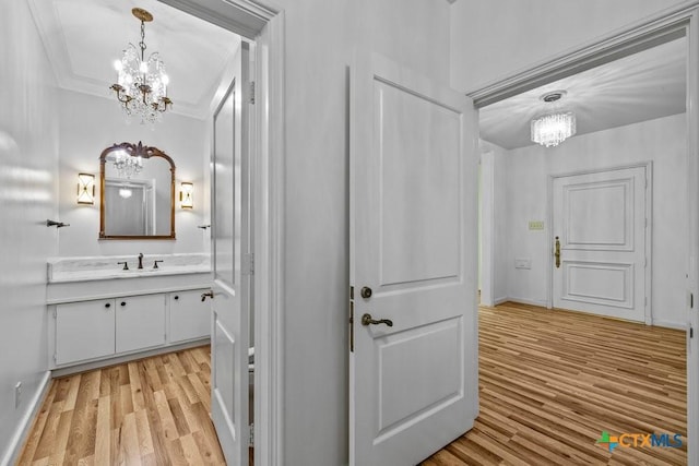 707 W Thompson Ave, Temple, TX 76501 - hallway with a chandelier, light wood-style flooring, a sink, ornamental molding, and baseboards