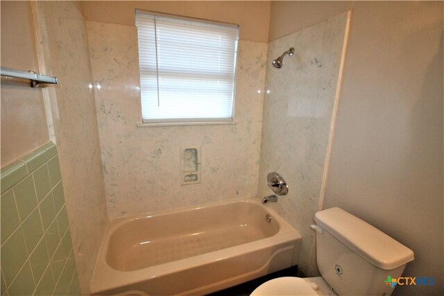 bathroom with tiled shower / bath combo and toilet