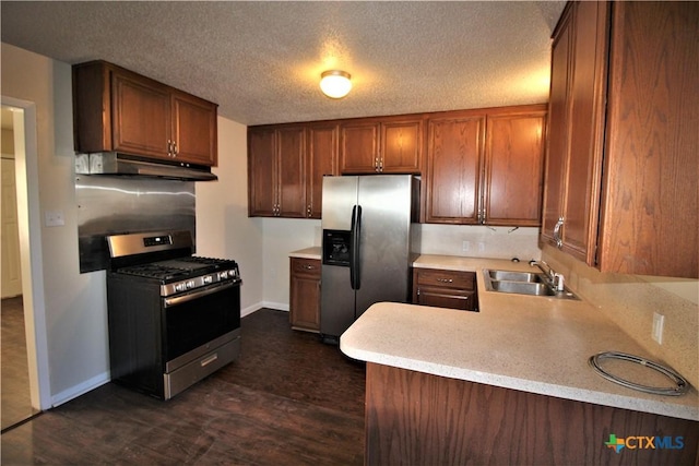 kitchen featuring sink, stainless steel appliances, dark hardwood / wood-style flooring, kitchen peninsula, and a textured ceiling