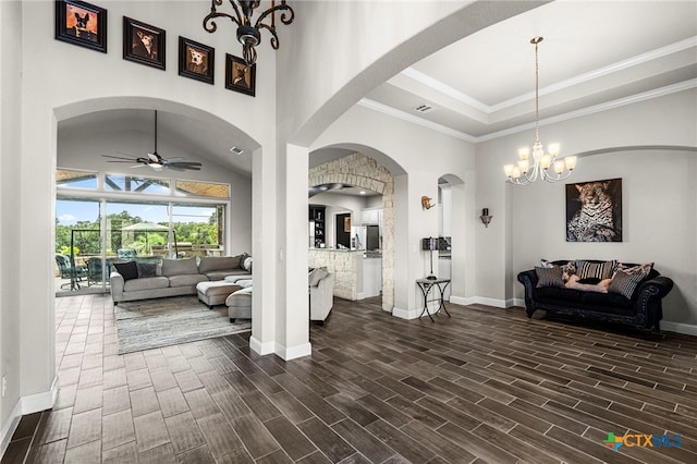 living room with a high ceiling, ceiling fan with notable chandelier, and crown molding