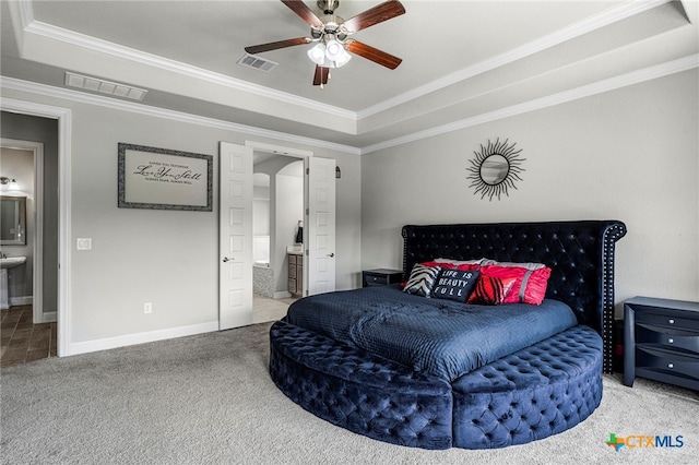 bedroom featuring ensuite bathroom, ceiling fan, a raised ceiling, and ornamental molding