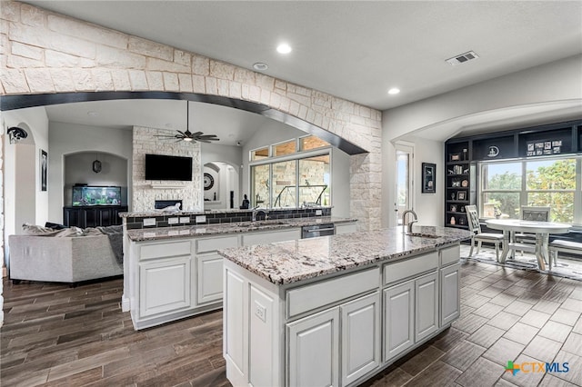 kitchen with white cabinets, a kitchen island with sink, dishwasher, and ceiling fan