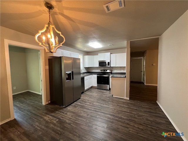 kitchen featuring appliances with stainless steel finishes, decorative light fixtures, backsplash, white cabinets, and dark wood-type flooring