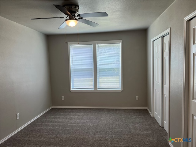 unfurnished bedroom featuring a textured ceiling, dark colored carpet, and ceiling fan