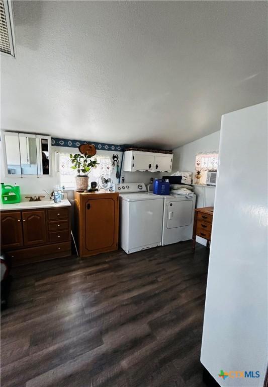 washroom featuring dark wood-type flooring, a textured ceiling, washer and clothes dryer, and sink