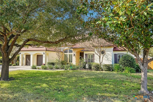 mediterranean / spanish house featuring a garage and a front yard