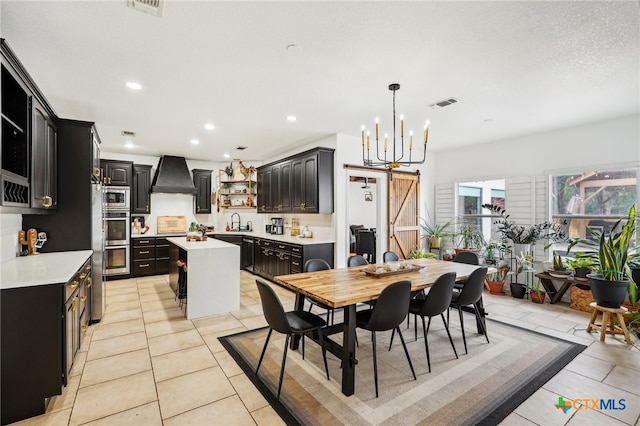 tiled dining area with a barn door, sink, and a notable chandelier