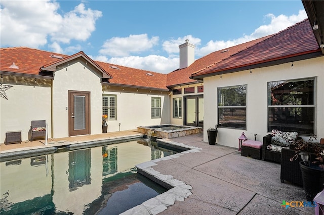 rear view of property with a swimming pool with hot tub and a patio area