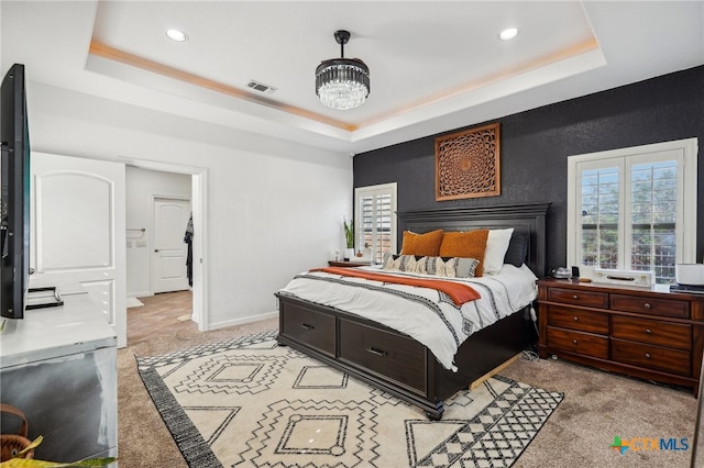 carpeted bedroom featuring a chandelier and a raised ceiling