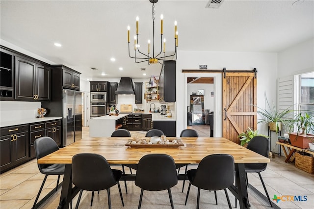 dining room with sink, an inviting chandelier, a barn door, and light tile patterned flooring