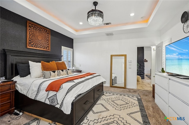 bedroom with light carpet, a chandelier, and a tray ceiling