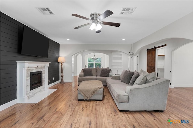 7031 Steinbeck Bend Dr, Waco, TX 76708 - living room featuring arched walkways, a barn door, light wood-style floors, ceiling fan, and a fireplace