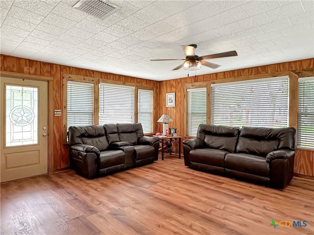 living room with wood walls, light hardwood / wood-style floors, and ceiling fan