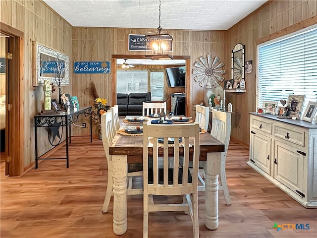 dining space with wood walls, a chandelier, and light hardwood / wood-style flooring