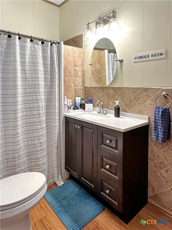 bathroom with tasteful backsplash, tile walls, vanity, hardwood / wood-style flooring, and toilet