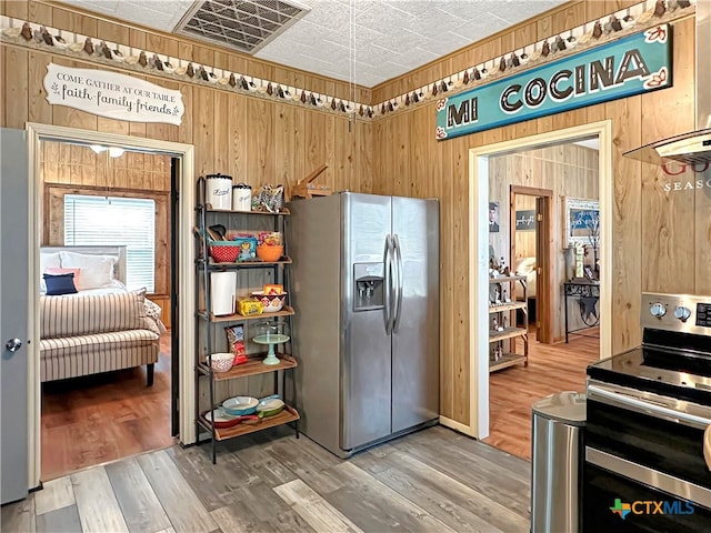 kitchen featuring hardwood / wood-style floors, stainless steel appliances, and wooden walls