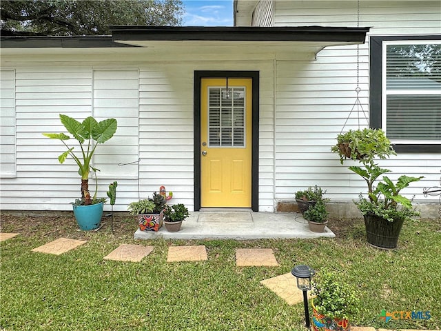 view of exterior entry with a yard and covered porch