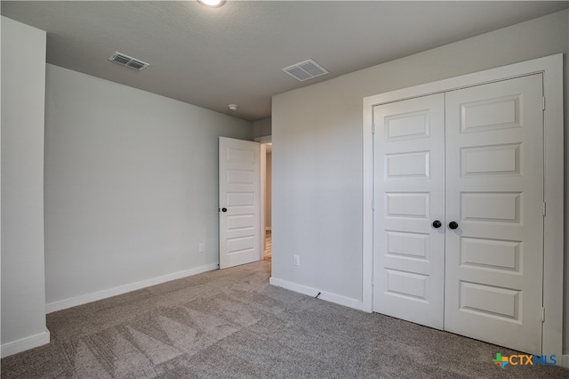 unfurnished bedroom featuring a closet, carpet, and a textured ceiling