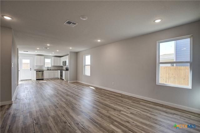 unfurnished living room featuring plenty of natural light, light hardwood / wood-style floors, and sink